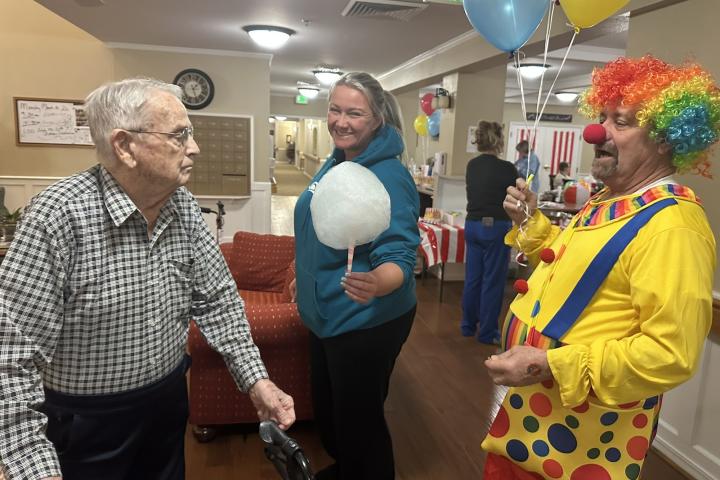 Misty Morrow with LifeTouch Health offers Ben some cotton candy, encouraged by Danny the clown.